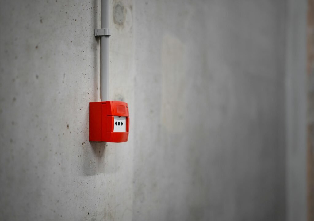 A red alarm box mounted on a gray concrete wall, offering urban security.